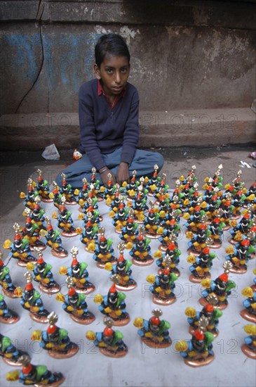 INDIA, Uttar Pradesh, Varanasi, Young boy selling figurines of Kala Bhairava outside Kala Bhairava Temple