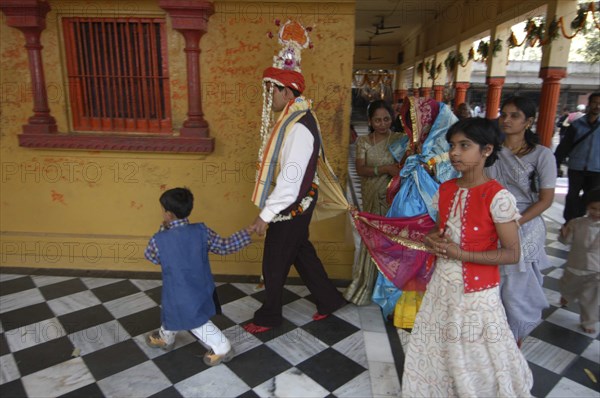 INDIA, Uttar Pradesh, Varanasi , Sankat Mochan Mandir temple. A groom walks around the temple sanctuary with his bride tied to him behind