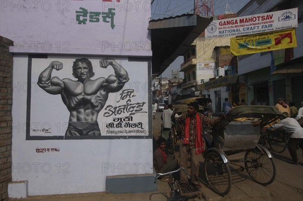 INDIA, Uttar Pradesh, Varanasi, A young Arnold Schwarzenegger painted on a poster for underwear with rickshaw driver nearby