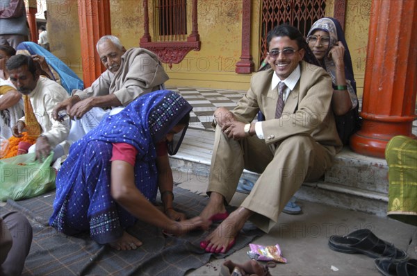 INDIA, Uttar Pradesh, Varanasi, Sankat Mochan Mandir temple. Hindu wedding with the groom getting his feet painted auspicious red as his mother sits behind him