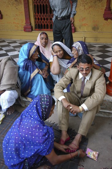 INDIA, Uttar Pradesh, Varanasi, Sankat Mochan Mandir temple. Hindu wedding with the groom getting his feet painted auspicious red as his mother sits behind him