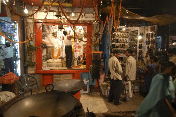 INDIA, Uttar Pradesh, Varanasi, Dasaswamedh Ghat. A man cleans the shrine of a Hindu saint in the market