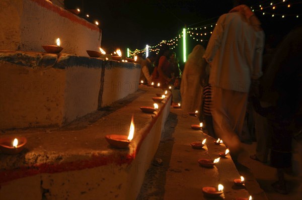 INDIA, Uttar Pradesh, Varanasi, Deep Diwali Festival. Oil lamps and crowds line the steps of the Ghats leading down to the Ganges River