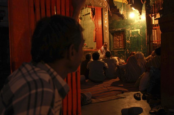 INDIA, Uttar Pradesh, Varanasi, Dasashwamedh Ghat. Hindus listen to a Bhramin pundit lecturing in a temple