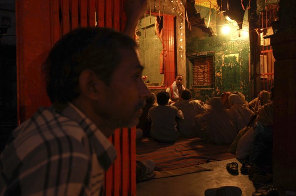 INDIA, Uttar Pradesh, Varanasi, Dasashwamedh Ghat. Hindus listen to a Bhramin pundit lecturing in a temple