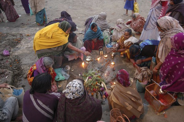 INDIA, Uttar Pradesh, Varanasi, Hindu women worshipping an earthen image of Hindu God Bhim at Asi Ghat
