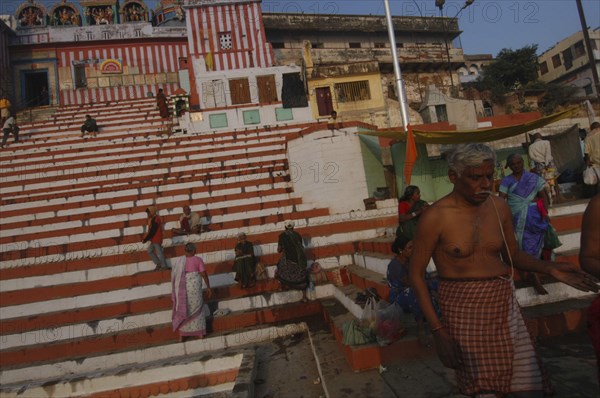 INDIA, Uttar Pradesh, Varanasi, Kedar Ghat. Hindu worshippers beside the Ganges River in the early morning with steps leading up to Kedara Mandir temple