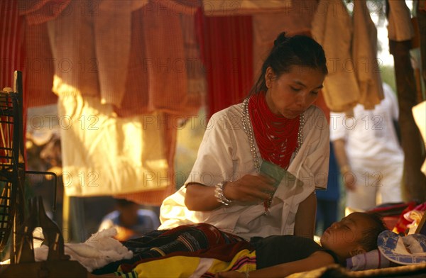 THAILAND, Chiang Mai Province, Lawa woman inside her house fanning her young sleeping son