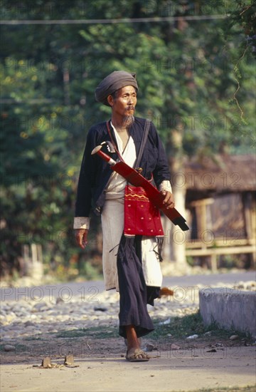 MYANMAR, Kachin State, Myitkyina, Manou grounds. Old Jinghpaw man in traditional attire with sword and shoulder bag