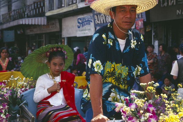 THAILAND, Chinag Mai, Young girl riding rickshaw driven by man in the Flower Festival Parade