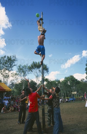THAILAND, Chiang Mai, Samathi Mai, Kachin Manou. Kachin boy reaches the prize climbing a greased bamboo pole