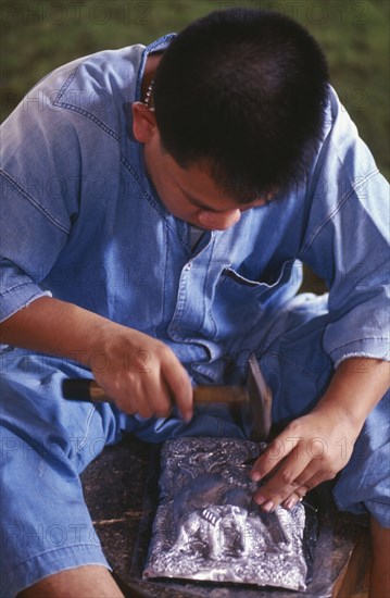 THAILAND, Chiang Mai, Wat Sri Suphan, Silversmith making repousse picture of elephants