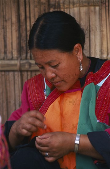 THAILAND, Chiang Mai Province, Lisu woman sewing in front of the house