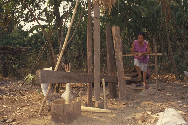 THAILAND, Chiang Mai Province, Mueng Keurt, Woman grinding coffee seeds with a foot powered mill to remove chaff