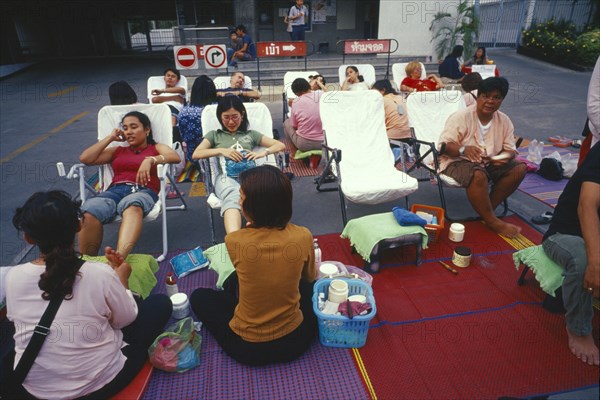 THAILAND, Chiang Mai, Masseurs and customers at a foot massage stall on Thaphae Road