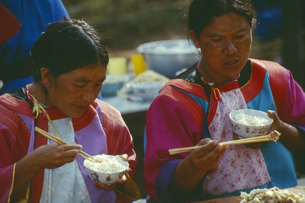 THAILAND, Chiang Rai Province, Doi Lan, Two Lisu women eating at the village priests house for the New Years festival