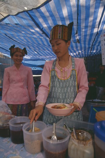 THAILAND, Chiang Mai, Wat Pa Pao, Two Shan women in traditional Shan attire at a food shop during Poi Sang Long