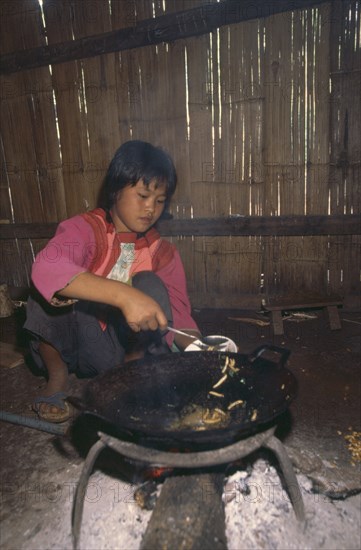 THAILAND, Chiang Rai Province, Doi Lan, Lisu girl putting cooked bamboo grubs in a bowl in her kitchen
