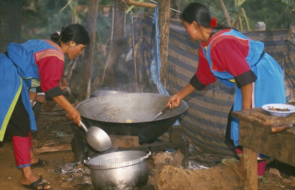 THAILAND, Chiang Rai Province, Huai Khrai, Lisu women stir frying a meal in a large wok for New Year dinner