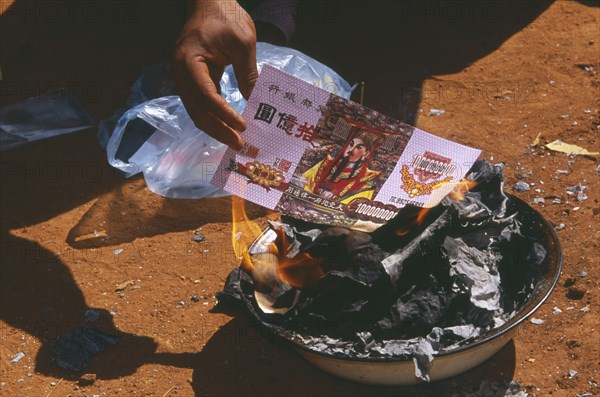 THAILAND, Chiang Mai Province, Bahn Mae Phaem, Lisu man burning imitation paper money for New Year