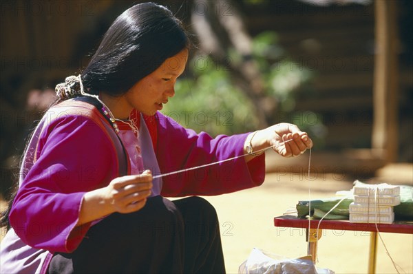 THAILAND, Chiang Mai Province, Bahn Mae Phaem, Lisu woman preparing string to be tied on familys wrists for good luck at New Year