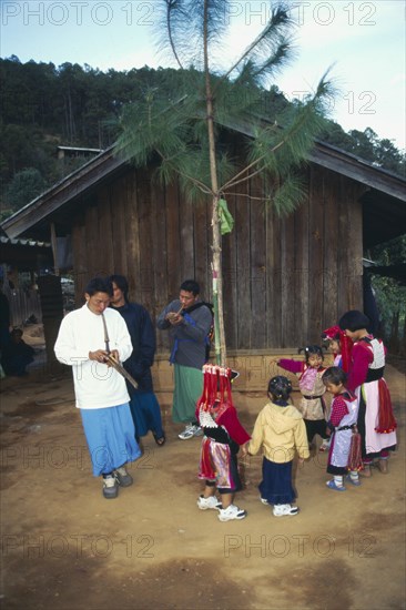 THAILAND, Chiang Rai Province, Doi Lan, Lisu men play gourd pipes as children dance around the New Year tree