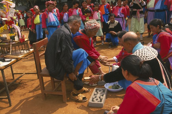 THAILAND, Chiang Rai Province, Huai Khrai, New Year. Lisu people paying respects to their elders by putting new socks on their feet