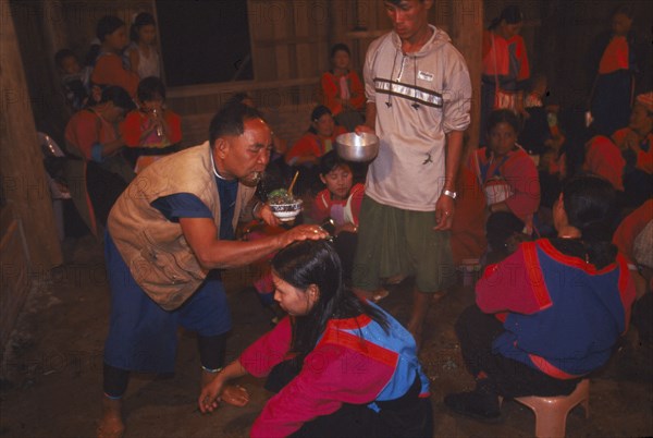 THAILAND, Chiang Rai Province, Doi Lan, Lisu shaman spraying supplicants head at healing ceremony