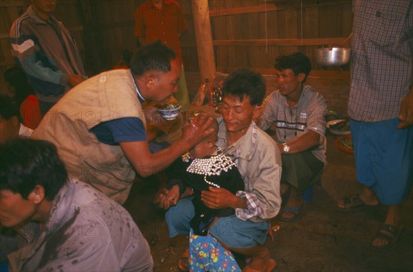 THAILAND, Chiang Rai Province, Doi Lan, Lisu shaman anointing supplicants head at healing ceremony