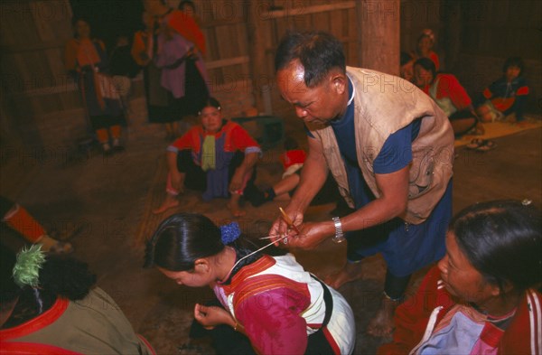 THAILAND, Chiang Rai Province, Doi Lan, Lisu shaman tying string around supplicants neck at healing ceremony