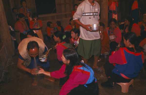 THAILAND, Chiang Rai Province, Doi Lan, Lisu shaman spraying supplicants hand at healing ceremony