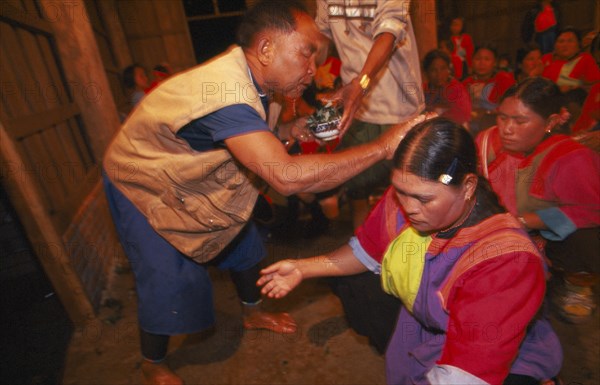 THAILAND, Chiang Rai Province, Doi Lan, Lisu shaman anointing supplicants head at healing ceremony