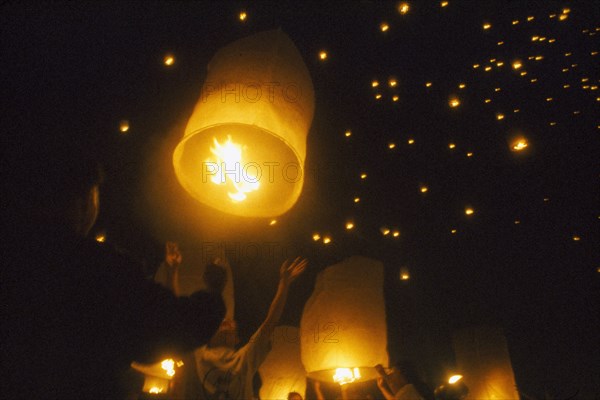 THAILAND, Chiang Mai, Mae Jo San Sai District, Loi Krathong Festival aka Yi Peng. People launching hot air balloons into the night sky