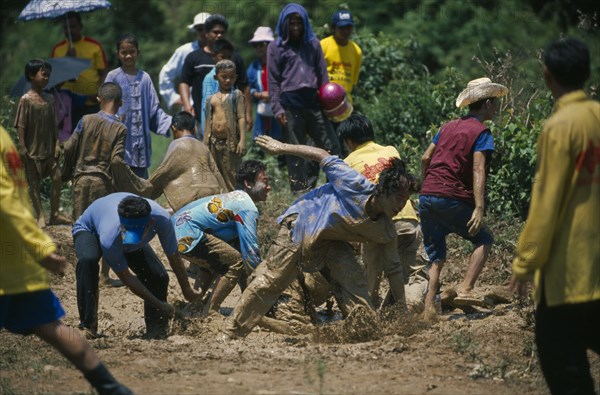 THAILAND, Yasothon, Young men frolicking in a mud pool during the Rocket Festival Bun Bang Fai