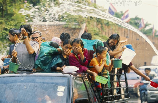 THAILAND, Chiang Mai, Songkran aka Thai New Year. Revellers in a pickup truck attempting to catch some of the water thrown at them
