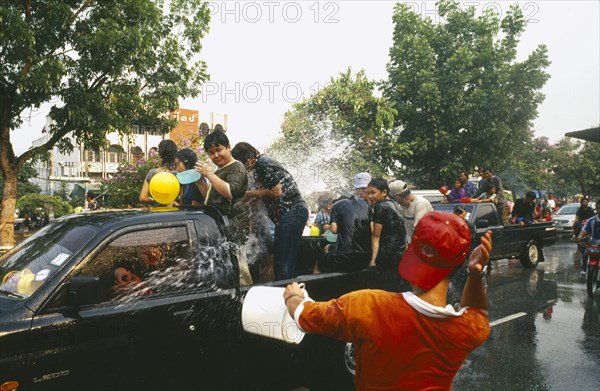 THAILAND, Chiang Mai, Songkran aka Thai New Year. Revellers in a pickup truck attempting to catch some of the water thrown at them