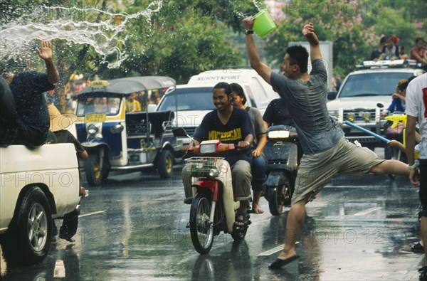 THAILAND, Chiang Mai, Songkran aka Thai New Year. Revellers in a pickup truck attempting to catch some of the water thrown at them over the heads of motorcyclists