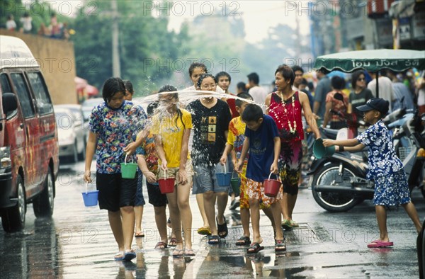 THAILAND, Chiang Mai, Songkran aka Thai New Year. Revellers having water thrown at them by a young boy