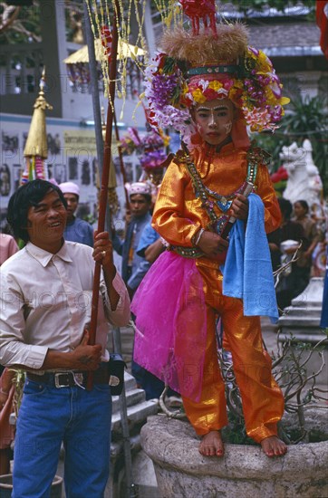 THAILAND, Chiang Mai, Shan Poi San Long. Crystal Children ceremony with Luk Kaeo in orange costume standing for photo at Wat Pa Pao