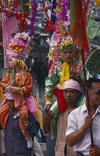 THAILAND, Chiang Mai, Shan Poi San Long. Crystal Children ceremony with 2 Luk Kaeo in costumes sitting on mens shoulders at Wat Pa Pao