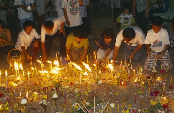 THAILAND, Chiang Mai, Wat Jedi Luang, Inthakhin Ceremony. People with offerings of flowers candles and joss sticks