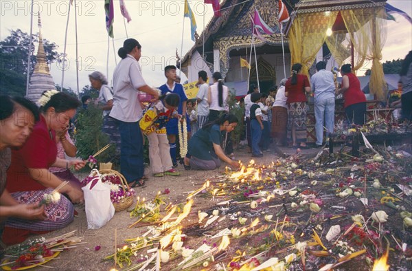 THAILAND, Chiang Mai, Wat Jedi Luang, Inthakhin Ceremony. People with offerings of flowers candles and joss sticks