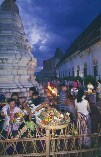 THAILAND, Chiang Mai, Wat Jedi Luang, Inthakhin Ceremony. People with offerings of flowers and joss sticks circimambulating