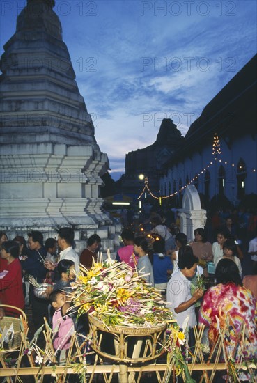 THAILAND, Chiang Mai, Wat Jedi Luang, Inthakhin Ceremony. People with offerings of flowers and joss sticks circimambulating