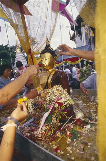 THAILAND, Chiang Mai, Wat Jedi Luang, Inthakhin Ceremony. Bathing Phra Fon Saen Ha Buddha statue surrounded by floral offerings and pool