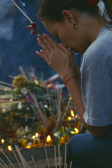 THAILAND, Chiang Mai, Wat Jedi Luang, Inthakhin Ceremony. Worshiper praying beside offerings