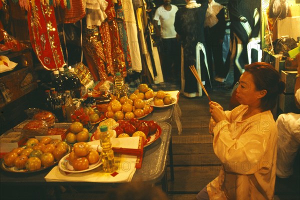 THAILAND, Chiang Mai, Female performer at the Chinese Opera offering joss sticks in prayer