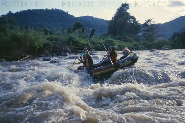 THAILAND, Chiang Mai Province, Western tourists and Thai guides white water river rafting on the Mae Taeng River