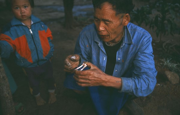 THAILAND, Chiang Rai Province, Doi Lan, Lisu elder reading a pair of chicken wings for oracular signs