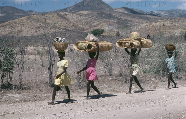 HAITI, Work, Line of girls carrying bags and baskets on their heads.